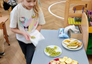 Dziewczynka częstuje się owocami.