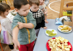 Chłopiec częstuje się owocami.