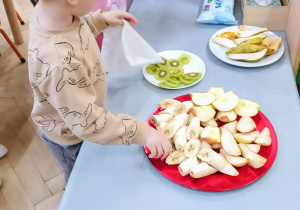 Chłopiec częstuje się owocami.