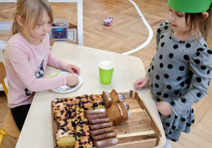 Dziewczynka częstuje dzieci ciastem.