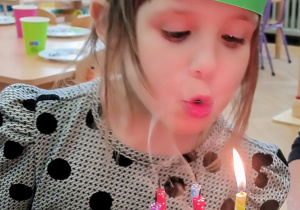 Dziewczynka zdmuchuje świeczki na torcie.
