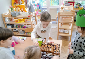 Dziewczynka częstuje dzieci ciastem.