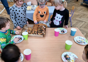 Dziewczynka częstuje dzieci ciastem.