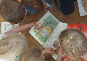 Na zdjęciu dzieci oglądające książkę
