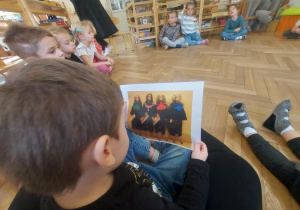 dziecko oglądające zdjęcie lalek w togach z różnymi kolorami żabotów