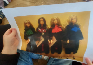 dziecko oglądające zdjęcie lalek w togach z różnymi kolorami żabotów