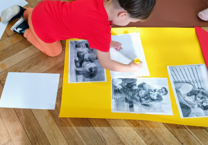 Chłopiec przykleja ilustrację do symbolicznego domu.