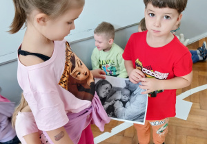 Chłopiec i dziewczynka pokazują ilustracje innym dzieciom.