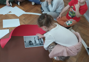 Dziewczynka przykleja ilustracje do symbolicznego domu.