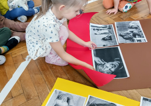 Dziewczynka przykleja ilustracje do symbolicznego domu.