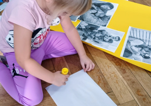 Dziewczynka przykleja ilustracje do symbolicznego domu.