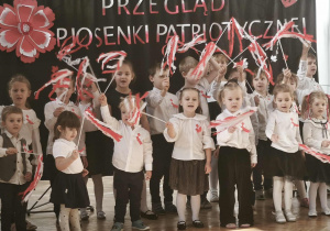 Grupa dzieci stoi i śpiewa piosenkę.