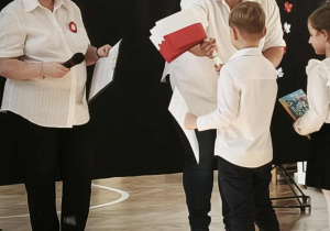 Panie wręczają dyplomy i flagi dzieciom.