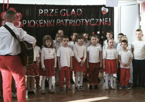 Grupa dzieci stoi i śpiewa piosenkę.