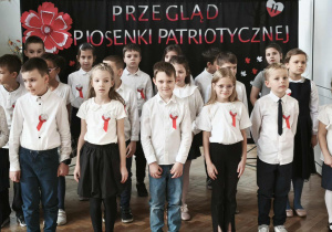 Grupa dzieci stoi i śpiewa piosenkę.