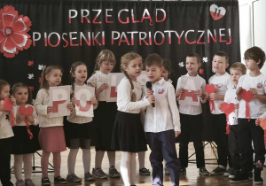 Grupa dzieci stoi i śpiewa piosenkę.
