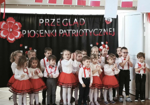 Grupa dzieci stoi i śpiewa piosenkę.