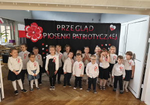 Grupa dzieci stoi i śpiewa piosenkę.