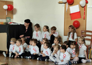 Grupa dzieci siedzi.