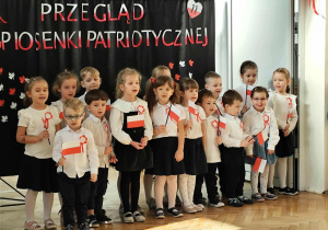 Grupa dzieci stoi i śpiewa piosenkę.