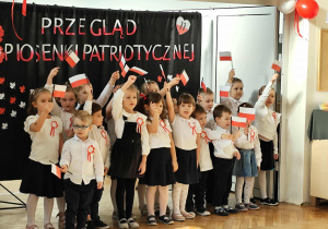 Grupa dzieci stoi i śpiewa piosenkę.