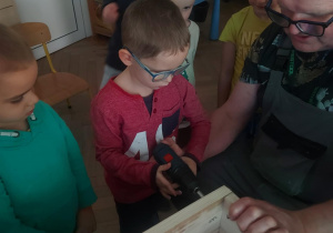 chłopiec za pomocą wkrętarki łączy elementy ściany