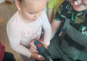 dziewczynka za pomocą wkrętarki łączy elementy