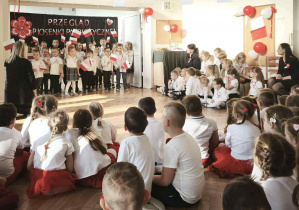 Zdjęcie przedstawia dzieci trzymające flagi w rączkach, podczas występu.