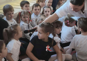 Zdjęcie przedstawia kobietę trzymającą mikrofon dziewczynce, gdy ta udziela odpowiedzi na pytanie.