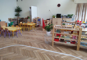 na zdjęciu widać salę przedszkolną grupy trzeciej, na pierwszym planie widac wyklejona na podłodze elipsę, niskie regały z materiałem rozwojowym dla dzieci