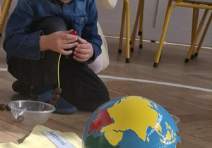 chłopiec nawleka korale na sznurek