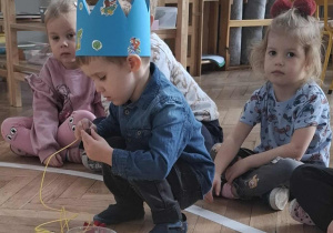 chłopiec nawleka korale na sznurek