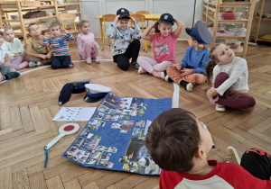 dzieci siedzą na podłodze, słuchają