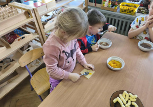 Na zdjęciu widzimy dziewczynkę, która smaruje kawałek wafla dżemem dyniowym.