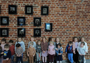 Na zdjęciu widzimy dzieci, które stają na ściance, na której wiszą zdjęcia aktorów Teatru Pinokio.