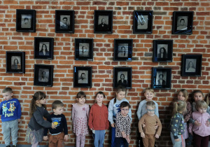Na zdjęciu widzimy dzieci, które stają na ściance, na której wiszą zdjęcia aktorów Teatru Pinokio.