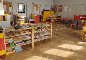 na zdjęciu widać salę przedszkolną grupy drugiej, na pierwszym planie widać niskie regały z materiałem rozwojowym dla dzieci, dalej wyklejoną na podłodze elipse