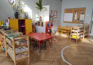 na zdjęciu widać salę przedszkolną grupy drugiej, niskie regały, stoliki czrwone i żółte oraz kawałek elipsy