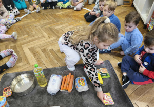 Na zdjęciu widzimy dziewczynkę, która kładzie na dywanik cukier wanilinowy, jako jeden ze składników ciasta marchewkowego.