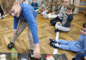 Na zdjęciu widzimy chłopca, który na dywanik kładzie tarkę.