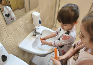 Na zdjęciu widzimy dziewczynki, które myją marchewki.