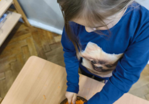 Na zdjęciu widzimy dziewczynkę, która trze marchewkę.