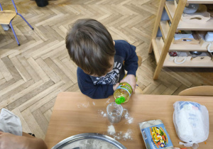 Na zdjęciu widzimy chłopca, który odmierza za pomocą szklanki olej.