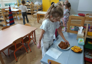 Na zdjęciu widzimy dziewczynkę, która wybiera kawałek ciasta marchewkowego, aby go zjeść.