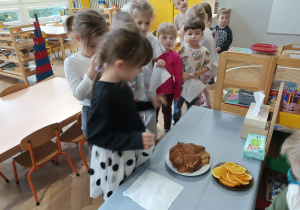 Na zdjęciu widzimy dziewczynkę, która wybiera kawałek ciasta marchewkowego, aby go zjeść.