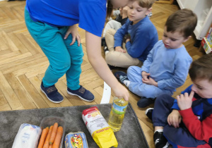 Na zdjęciu widzimy chłopca, który wyjął jeden ze składników ciasta marchewkowego z torby.