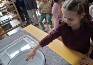 dziewczynka trzyma rękę nad miską z gorącą wodą