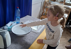 dziewczynka trzyma rękę nad miską z gorącą wodą