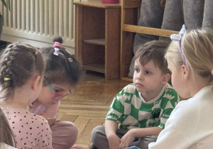 Zdjęcie przedstawia dzieci w kółeczku podczas wykonywania zadania.