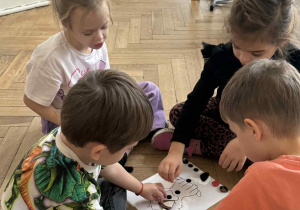 Zdjęcie przedstawia dzieci przyczepiające elementy do planszy.